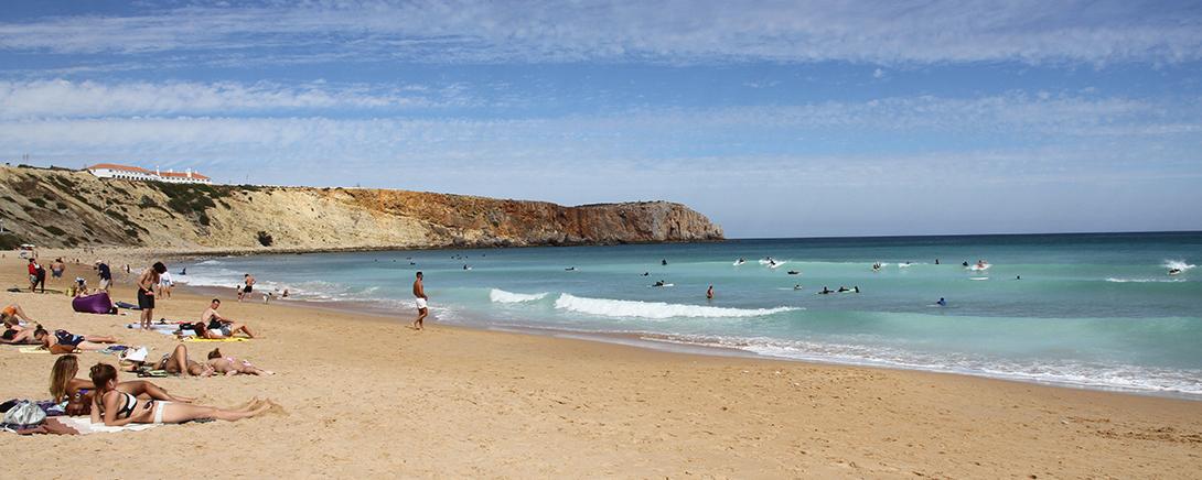 Zonnig strand met surfers en zwemmers