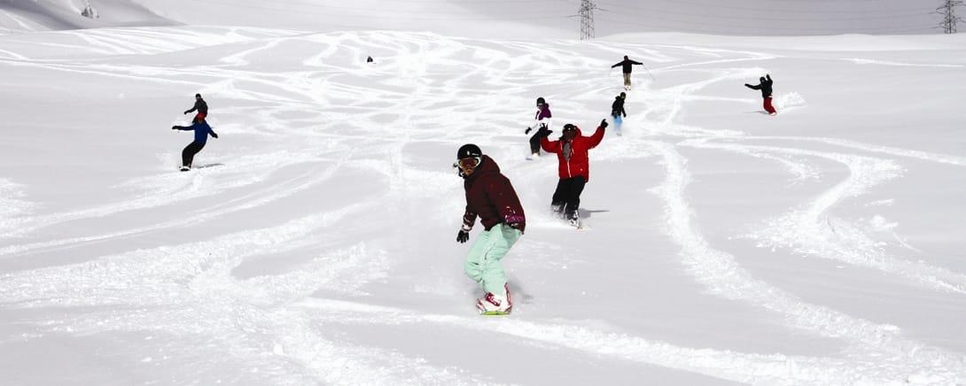 Skiërs en snowboarders op een brede piste in Laax