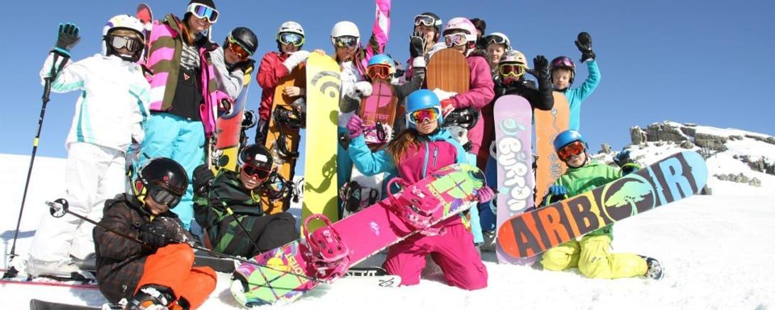 Groep kinderen met snowboards op de berg in Laax