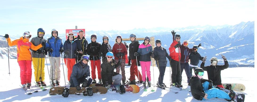 Family Jam groep met ski's en snowboards op de bergtop