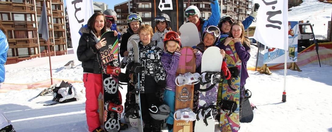 Groep kinderen met snowboards voor de residence in Val Claret