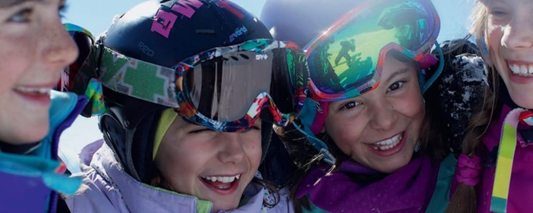 Kinderen met skibrillen lachen in de sneeuw in Laax